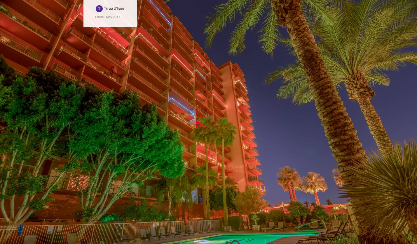 Landmark Towers, the full 17-story tower lit at night above the pool and palm trees